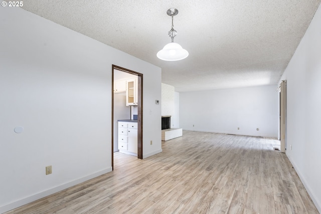 224 N Hayden Bay Dr, Portland, OR 97217 - spare room featuring light wood finished floors, a brick fireplace, and a textured ceiling
