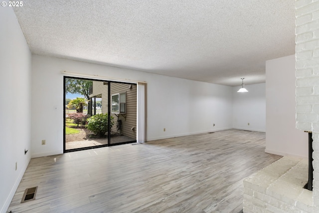 224 N Hayden Bay Dr, Portland, OR 97217 - unfurnished living room featuring a textured ceiling, light wood-style flooring, and a fireplace