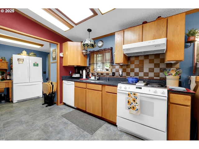 kitchen featuring dark countertops, a sink, white appliances, decorative backsplash, and under cabinet range hood
