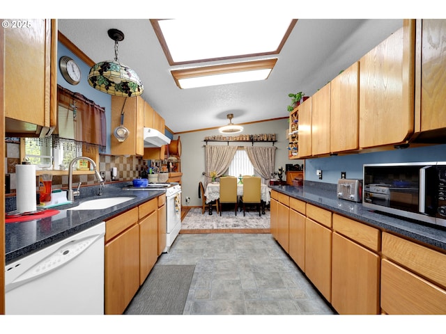 kitchen with crown molding, dark countertops, a sink, under cabinet range hood, and white appliances