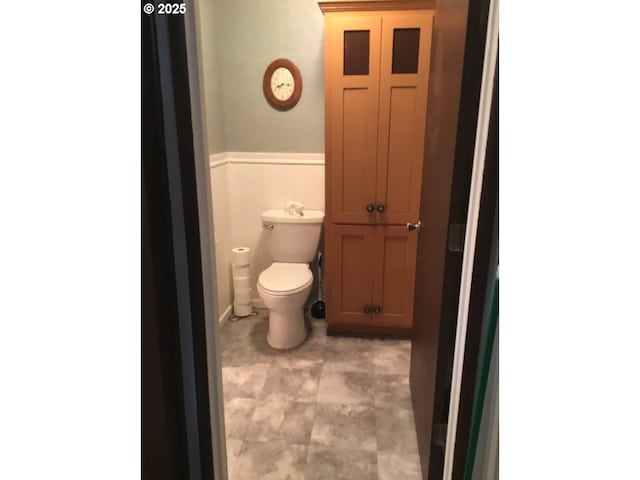 bathroom featuring wainscoting and toilet