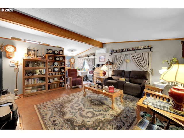 living area with lofted ceiling with beams, a textured ceiling, a wall unit AC, and wood finished floors