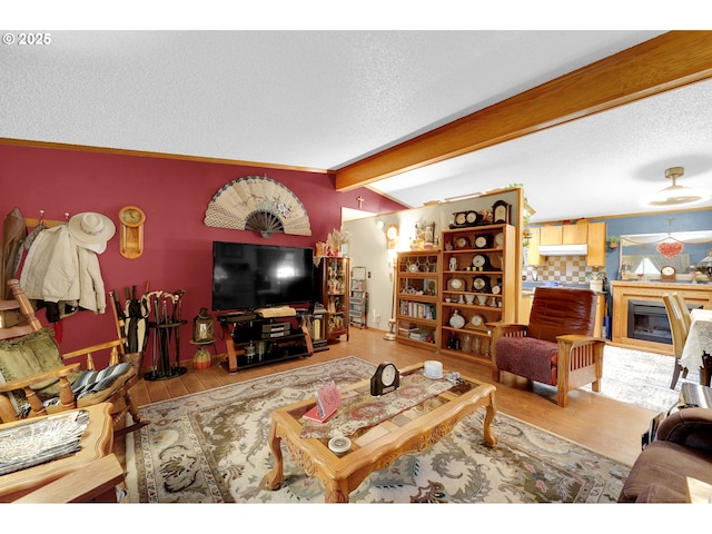 living room with a textured ceiling, vaulted ceiling with beams, a fireplace, and wood finished floors