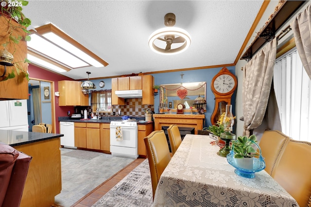 kitchen featuring a textured ceiling, dark countertops, a sink, under cabinet range hood, and white appliances