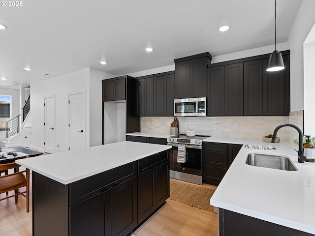 7195 SE Crystal Springs Blvd Unit 7, Portland, OR 97206 - kitchen with appliances with stainless steel finishes, light wood-type flooring, dark cabinets, tasteful backsplash, and light countertops