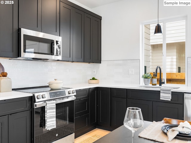 7195 SE Crystal Springs Blvd Unit 7, Portland, OR 97206 - kitchen featuring stainless steel appliances, backsplash, light countertops, and hanging light fixtures