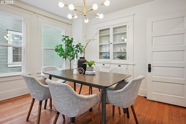 dining area with light wood finished floors and a notable chandelier
