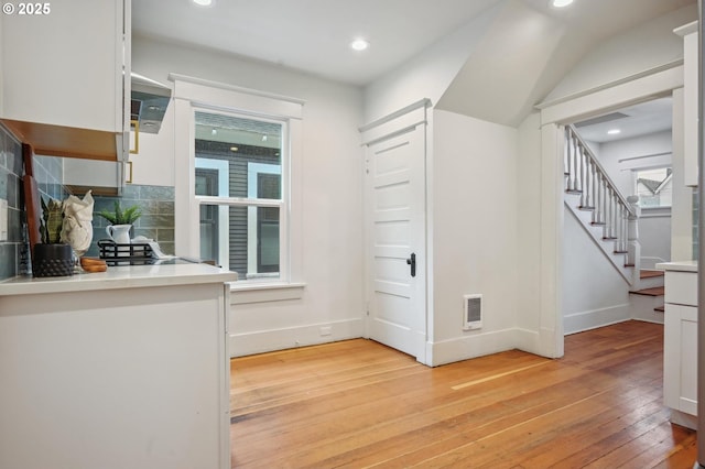 4131 NE Cleveland Ave, Portland, OR 97211 - kitchen with light wood-style flooring, white cabinets, tasteful backsplash, recessed lighting, and light countertops