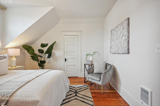 bedroom with baseboards, wood finished floors, and visible vents