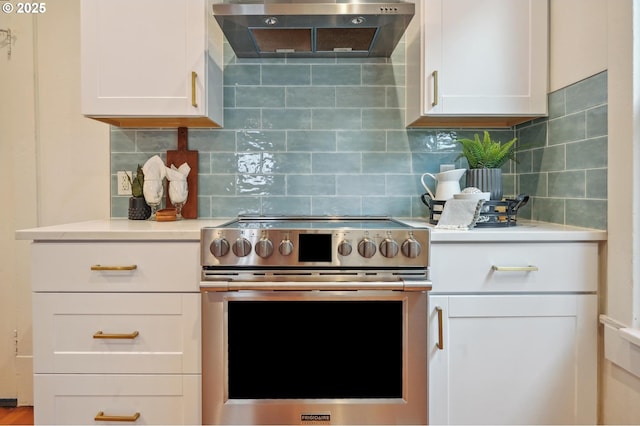 4131 NE Cleveland Ave, Portland, OR 97211 - kitchen with stainless steel electric stove, range hood, light countertops, decorative backsplash, and white cabinetry