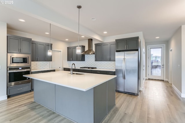 kitchen with stainless steel appliances, light wood-type flooring, a sink, and wall chimney exhaust hood