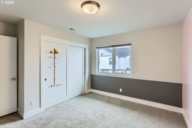 unfurnished bedroom featuring carpet, baseboards, visible vents, and a closet