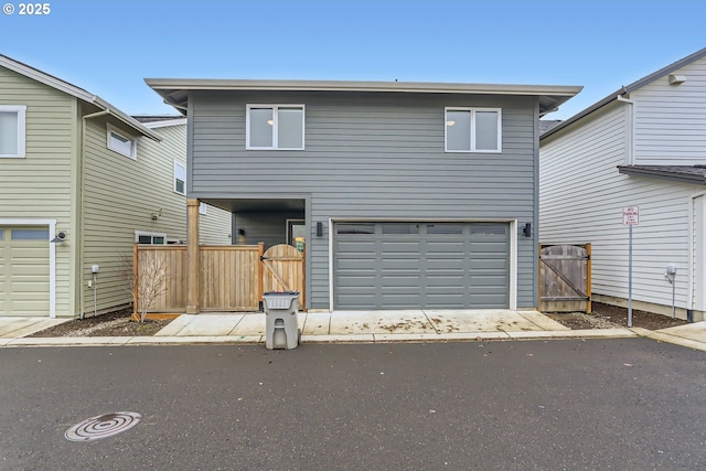 view of front facade with a gate, fence, driveway, and an attached garage