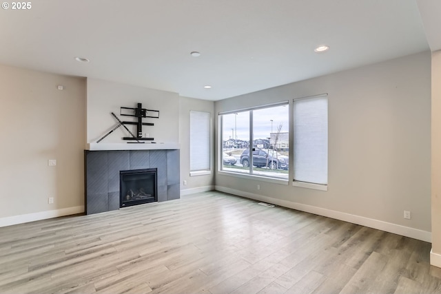 unfurnished living room with a fireplace, baseboards, wood finished floors, and recessed lighting