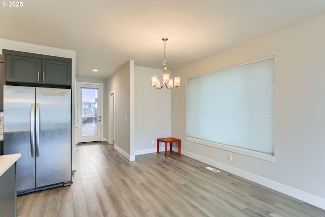 unfurnished dining area featuring a notable chandelier, recessed lighting, visible vents, baseboards, and light wood finished floors