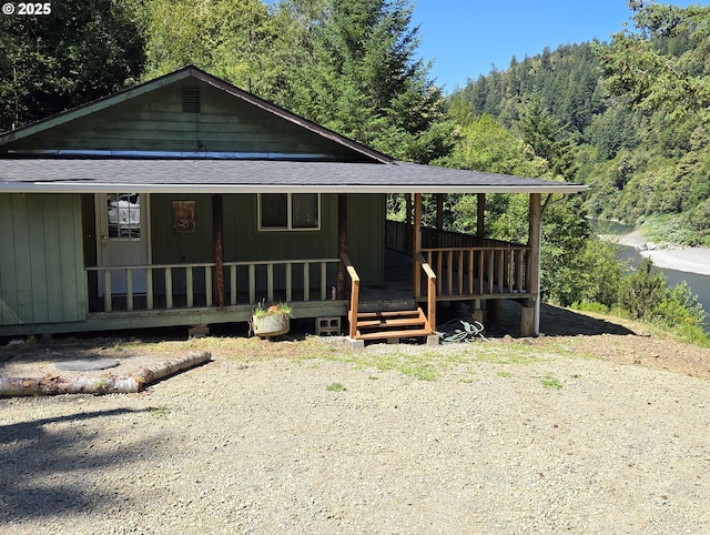 33080 Lupine Way Rd, Gold Beach, OR 97444 - view of front of house with roof with shingles, a view of trees, and covered porch