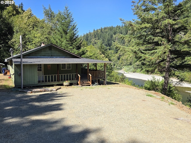 33080 Lupine Way Rd, Gold Beach, OR 97444 - view of front facade with covered porch, a view of trees, a shingled roof, and board and batten siding