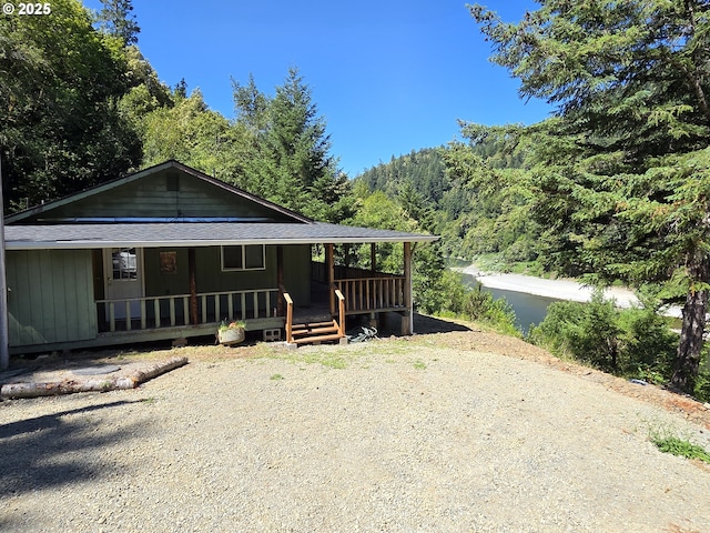 33080 Lupine Way Rd, Gold Beach, OR 97444 - view of front facade featuring covered porch, a shingled roof, and a wooded view