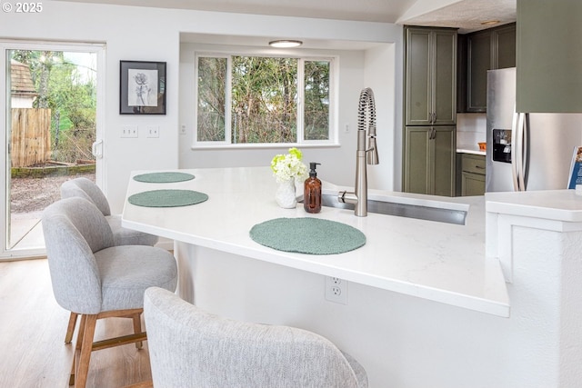 kitchen with a sink, stainless steel fridge, wood finished floors, and light countertops