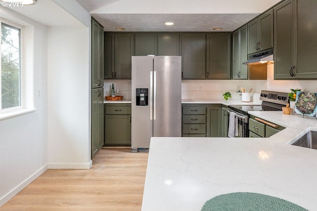 kitchen featuring baseboards, light wood finished floors, under cabinet range hood, appliances with stainless steel finishes, and green cabinets