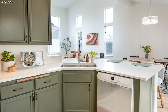 kitchen with dishwasher, a peninsula, a wealth of natural light, and green cabinets