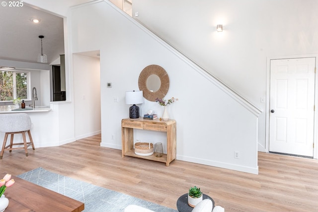 unfurnished living room featuring light wood-style floors, baseboards, and a sink