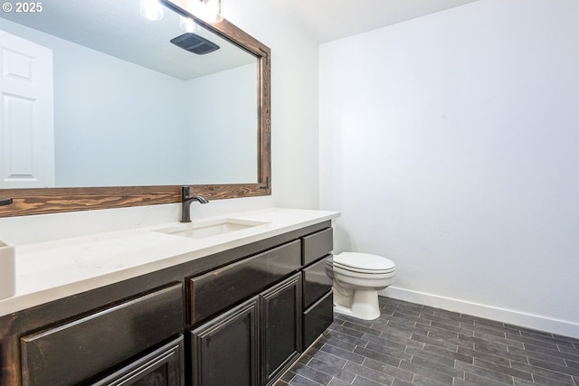 bathroom with vanity, toilet, visible vents, and baseboards