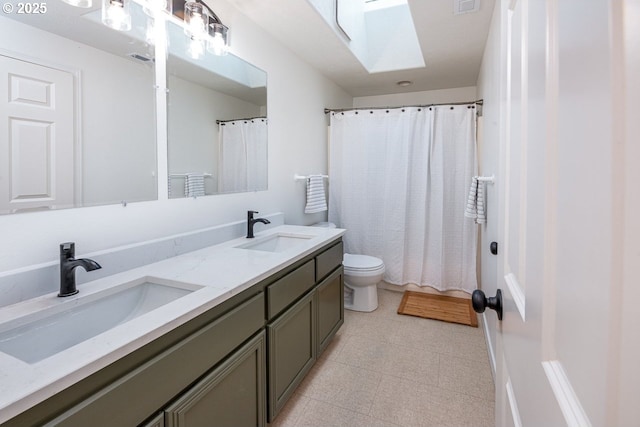 bathroom with double vanity, toilet, a skylight, and a sink