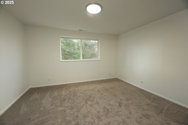 carpeted spare room with visible vents and baseboards