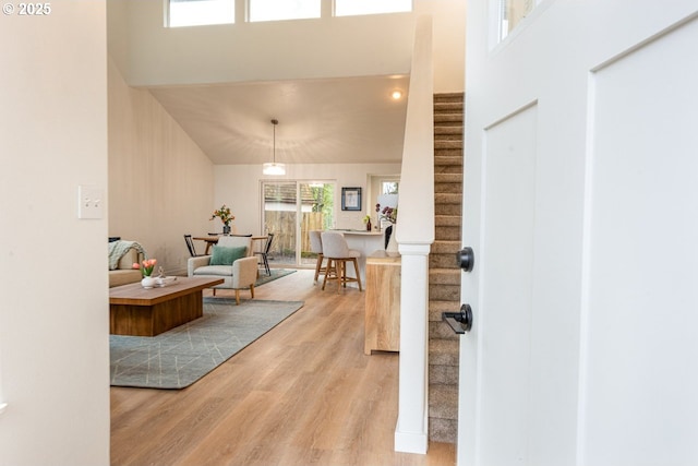 entryway featuring stairs, a high ceiling, and light wood finished floors