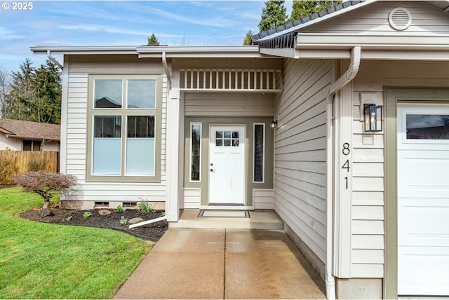 view of exterior entry with crawl space, a garage, and fence