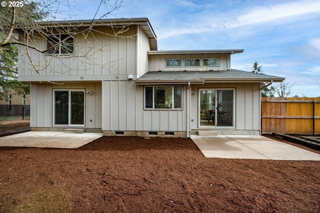 rear view of house featuring board and batten siding, fence, roof with shingles, a balcony, and a patio area