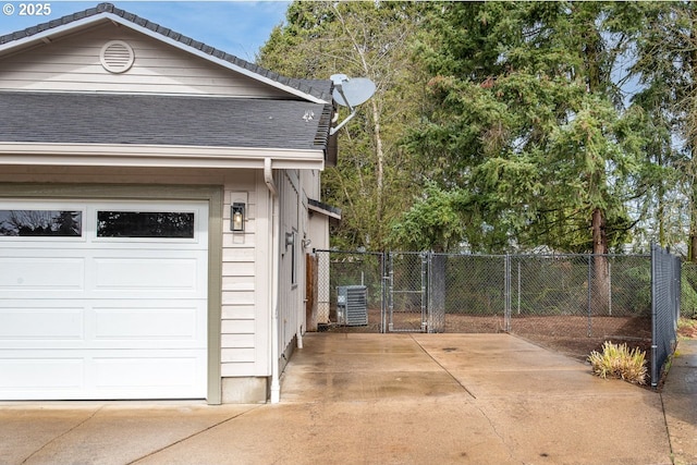 garage with a gate, central AC, and fence