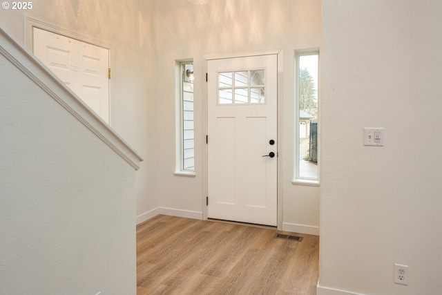 foyer featuring visible vents, baseboards, a healthy amount of sunlight, and light wood finished floors