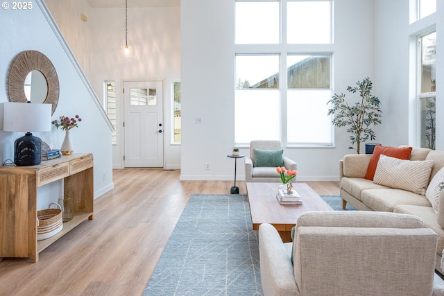 living room with light wood finished floors, baseboards, and a towering ceiling