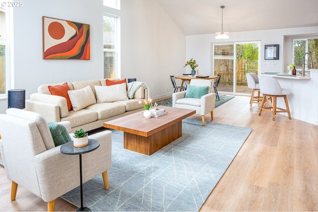 living area with lofted ceiling, light wood-style floors, and baseboards