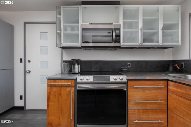 3109 NW Neptune Ave, Lincoln City, OR 97367 - kitchen featuring stainless steel appliances, brown cabinetry, and glass insert cabinets