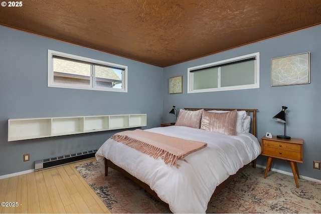 3109 NW Neptune Ave, Lincoln City, OR 97367 - bedroom featuring a baseboard heating unit, hardwood / wood-style floors, and ornamental molding