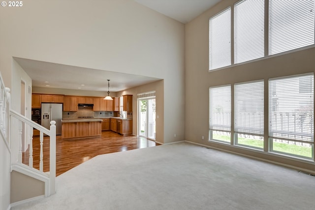 13605 NW Hogan St, Portland, OR 97229 - unfurnished living room with light colored carpet, plenty of natural light, a towering ceiling, baseboards, and a sink