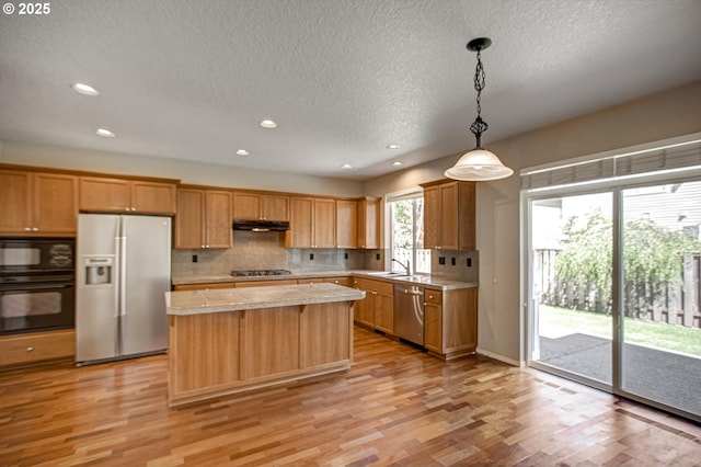 13605 NW Hogan St, Portland, OR 97229 - kitchen featuring black appliances, a sink, under cabinet range hood, tasteful backsplash, and light wood finished floors