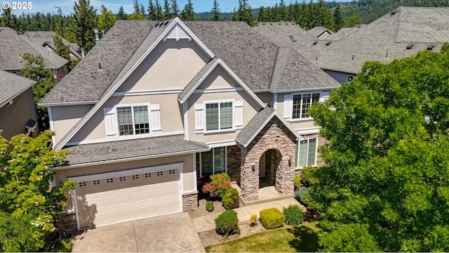 13605 NW Hogan St, Portland, OR 97229 - view of front of house with stucco siding, stone siding, driveway, and a garage