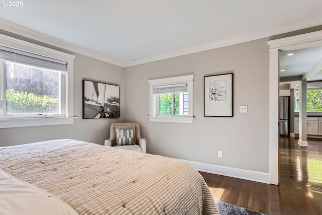 bedroom featuring multiple windows, baseboards, wood finished floors, and freestanding refrigerator