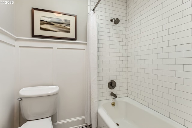 full bathroom featuring shower / tub combo, wainscoting, a decorative wall, and toilet