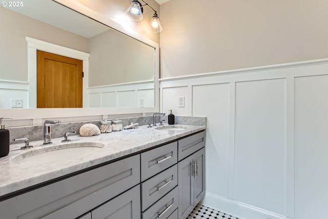 full bath with double vanity, a decorative wall, and a sink