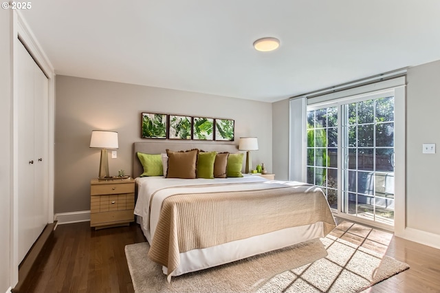 bedroom with access to outside, a closet, baseboards, and wood finished floors