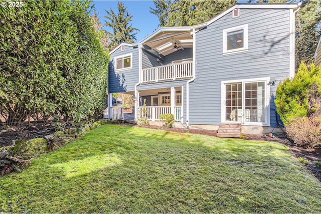 back of house featuring a balcony, ceiling fan, and a lawn