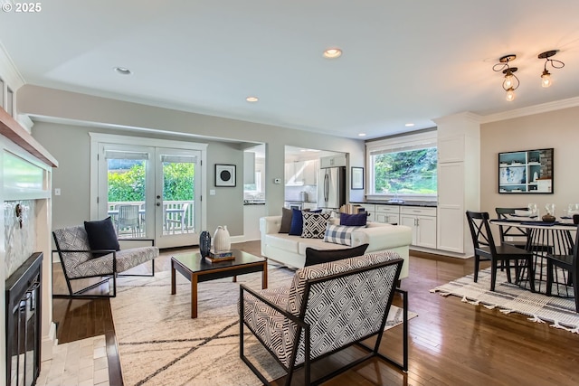 living area with ornamental molding, recessed lighting, french doors, and light wood finished floors