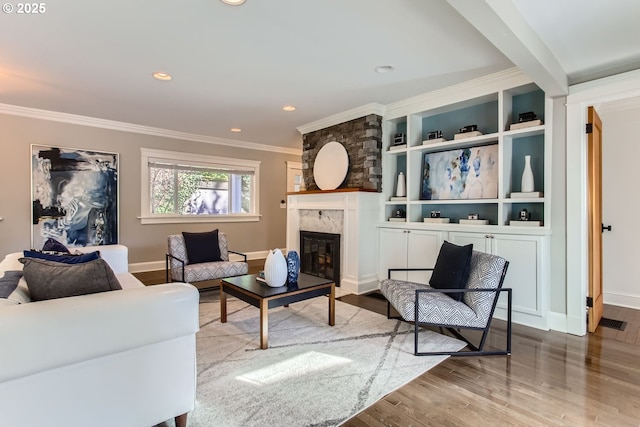 living area with baseboards, wood finished floors, crown molding, a fireplace, and recessed lighting