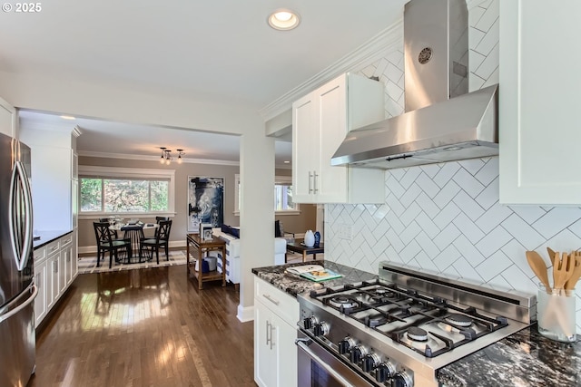 kitchen with appliances with stainless steel finishes, white cabinets, crown molding, and wall chimney exhaust hood