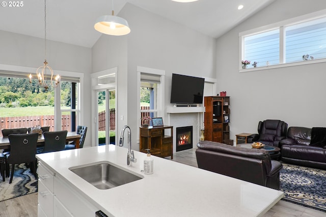 kitchen featuring a chandelier, a sink, white cabinets, open floor plan, and light countertops